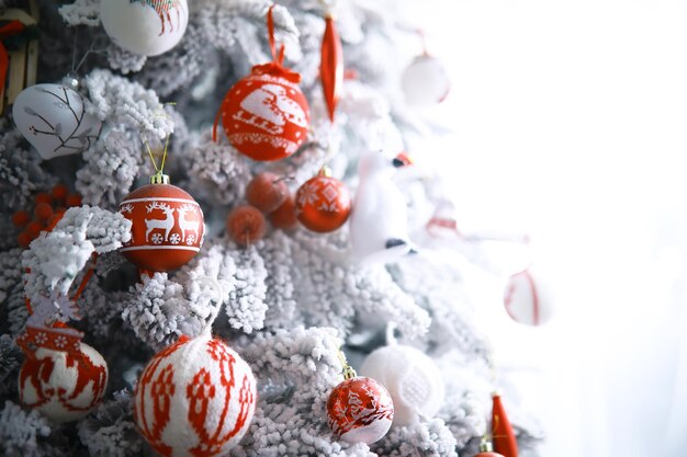Fundo de férias de Natal. Bugiganga prateada e colorida pendurada em uma árvore decorada com bokeh e neve, copie o espaço.