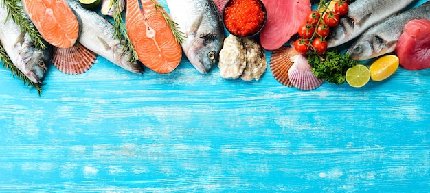 Fundo de frutos do mar: salmão, atum, caviar, ostras, peixes dourados e crustáceos em um fundo azul de madeira. vista do topo. frutos do mar.