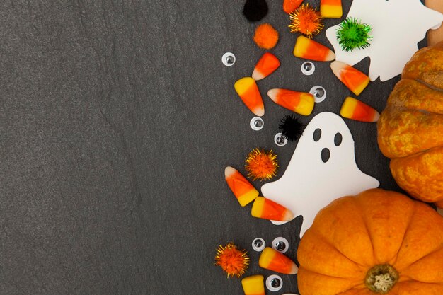 Fundo de Halloween com fantasmas e milho doce em um fundo de ardósia