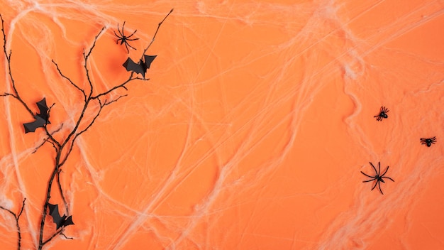 Fundo de Halloween com teia de aranha e morcegos de papel voando em galho de árvore em fundo laranja