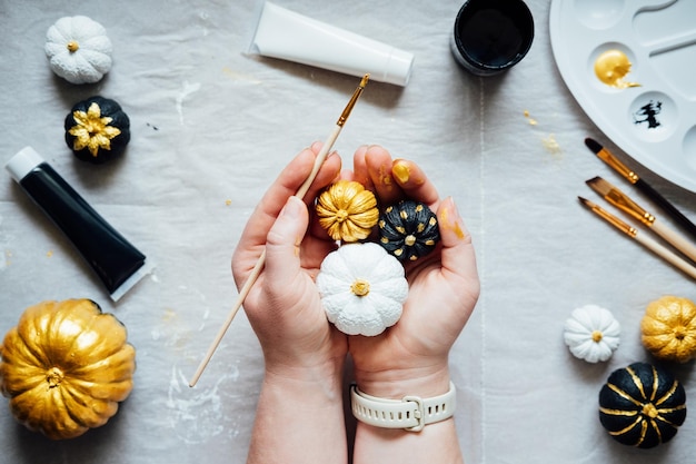 Fundo de ideias de artesanato de Halloween com mãos femininas de abóbora de halloween preta e dourada com criatividade