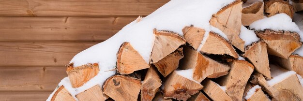 Fundo de lenha texturizado madeira picada para acender e aquecer lenha empilhada em pilha de bétula coberta de neve congelada fresca e flocos de neve clima frio e inverno nevado banner de temporada