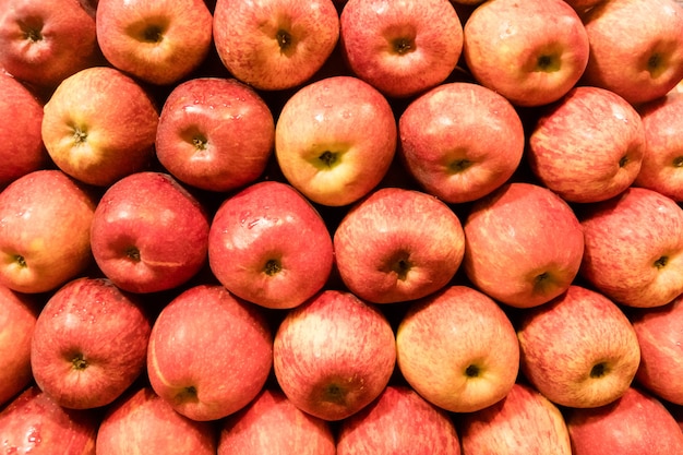 Fundo de maçãs vermelhas. frutas maduras dispostas ordenadamente no balcão da loja