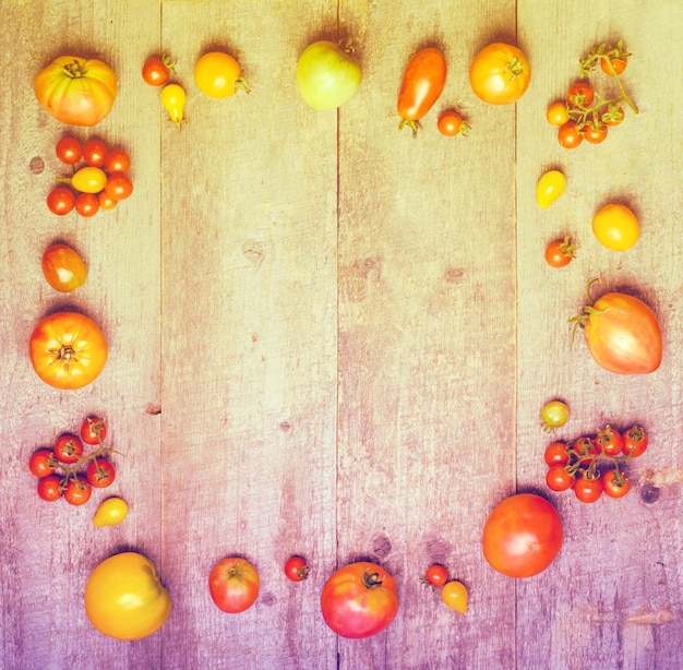 Foto fundo de madeira com moldura de tomates vermelhos frescos e maduros