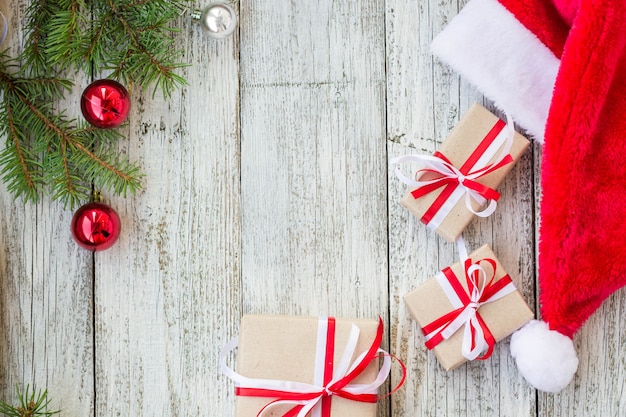 Fundo de madeira de férias de natal com ramos de abeto, chapéu de papai noel e caixas de presente