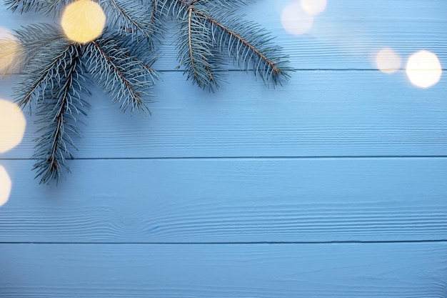 Fundo de madeira de natal e ano novo com galhos de árvores de abeto azul e espaço de cópia de luzes