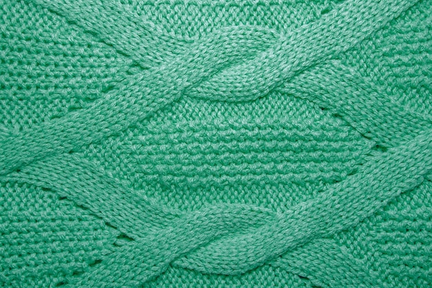 Fundo de malha de malha com um padrão de relevo. Textura de suéter de lã verde close-up