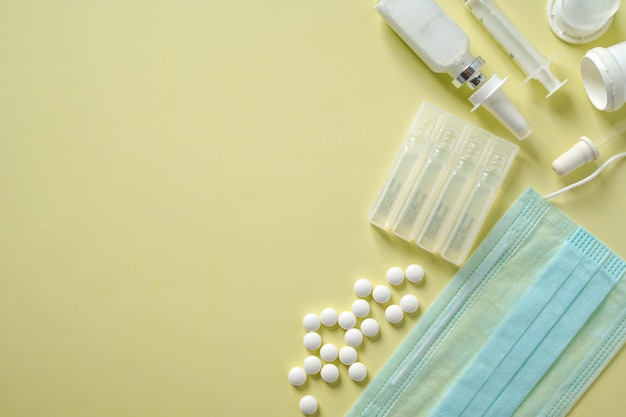 Fundo de medicina com pacotes de máscaras médicas de frasco de vidro de comprimidos e ampolas no fundo bege com espaço de cópia Foto de alta qualidade