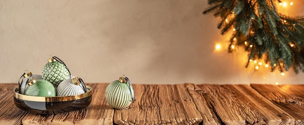 Fundo de Natal aconchegante de cor pastel com enfeites em tigela preta na mesa de madeira e coroa de flores na parede