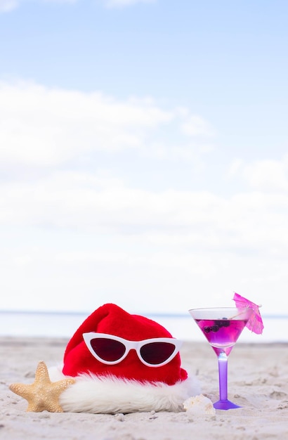 Fundo de Natal chapéu de Papai Noel na praia com estrela do mar e coquetel de verão