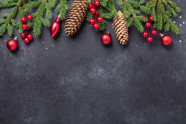 Fundo de natal com árvore do abeto, azevinho e bolas vermelhas em fundo de pedra escura. vista superior copiar espaço - imagem