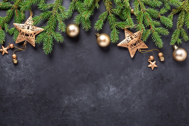 Fundo de Natal com árvore do abeto e bolas douradas e estrelas no fundo de pedra escura. Vista superior Copiar espaço - Imagem