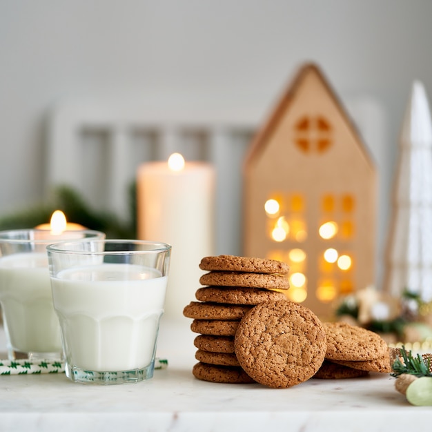 Fundo de Natal com biscoitos de aveia e gengibre, dois copos de leite aconchegante à noite na cozinha