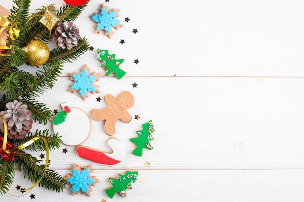 Fundo de natal com cones de galhos de abeto de presente de biscoitos planos e espaço de cópia em fundo branco de madeira