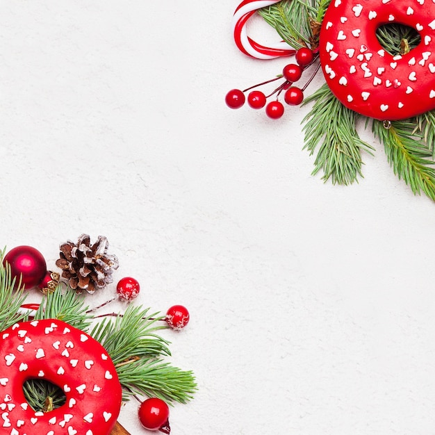 Fundo de natal com donuts doces bagas de azevinho e galho de abeto verde sobre fundo de textura de estuque branco Vista superior plana de Natal com espaço de cópia