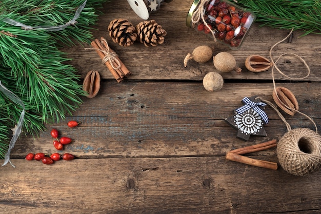 Fundo de Natal com galhos de pinheiro, canela, frutas e cones.