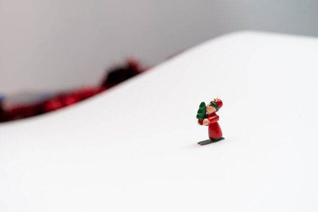 Fundo de Natal com pequenos personagens de decoração de árvore nevando em uma montanha de papel branco