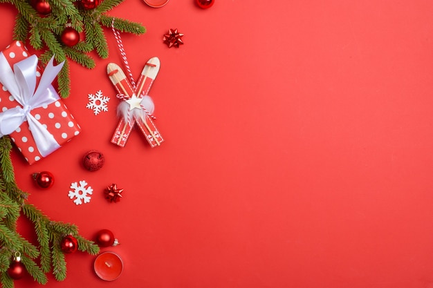 Fundo de Natal com presentes, bolas de vidro e galhos de pinheiro em um fundo vermelho. Composição de decorações de Natal de ano novo. Copie o espaço. Camada plana, vista superior.