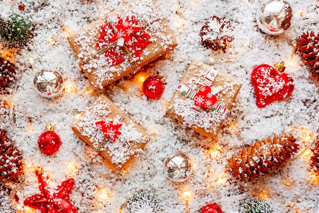 Fundo de Natal com presentes, fitas, bolas e decorações diferentes na neve com lâmpadas.