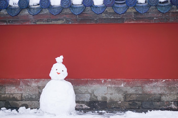 Fundo de natal com um boneco de neve fofo no fundo da parede de tijolos vermelhos