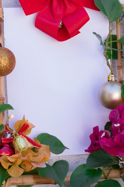 Foto fundo de natal com um cartão branco em branco para carta-convite ou e-mail marketing de entrada. cercado por decorações festivas e verdadeiras flores vermelhas e douradas. imagem de conceito sustentável.