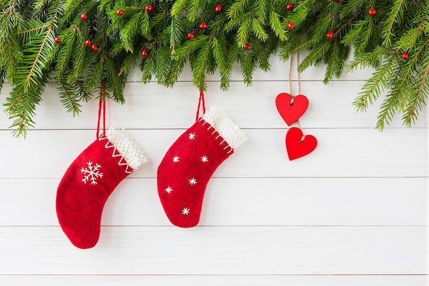 Fundo de natal. Coração vermelho e meias vermelhas de Natal em fundo branco de madeira, árvore de Natal.