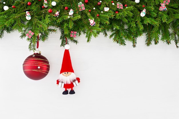 Fundo de natal. Galho de árvore do abeto de Natal com Papai Noel e bola vermelha de Natal em fundo branco de madeira. copyspace, vista superior