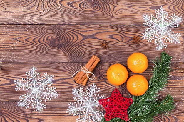 Fundo de Natal - galhos de pinheiro, pinha, flocos de neve e tangerinas, decoração de ano novo em uma mesa de madeira. Postura plana, copie o espaço.