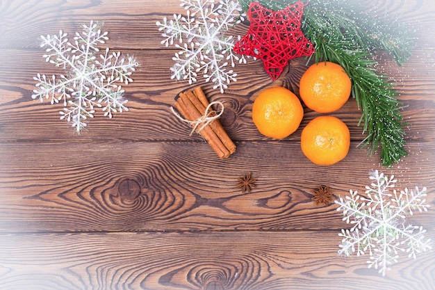 Fundo de Natal - galhos de pinheiro, pinha, flocos de neve e tangerinas, decoração de ano novo em uma mesa de madeira. Postura plana, copie o espaço.