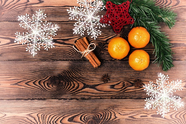 Fundo de Natal - galhos de pinheiro, pinha, flocos de neve e tangerinas, decoração de ano novo em uma mesa de madeira. Postura plana, copie o espaço.