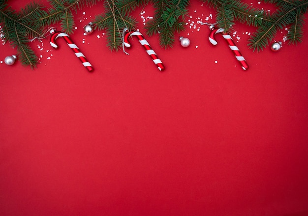 Foto fundo de natal minimalista flatlay vermelho com galhos de pinheiro e doces, árvore de natal e brinquedos
