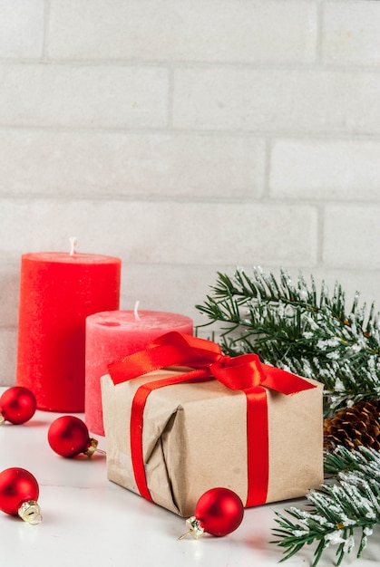 Fundo de Natal para cartão de felicitações. Galhos de árvore de Natal com efeito de neve com fita vermelha festiva, pinhas, caixas de presente e velas, em fundo de mármore branco