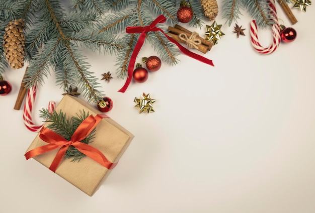 Fundo de natal para cartão de saudação galhos de árvores de natal com efeito de neve com caixas de presente de pinhas de fita vermelha festiva e velas no espaço de cópia de fundo de mármore branco