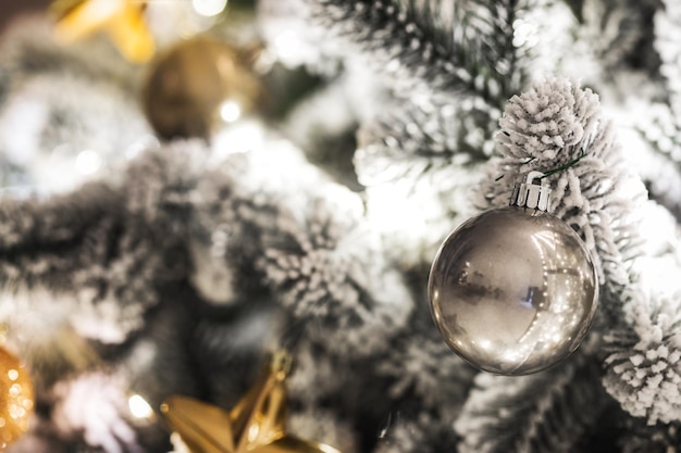 Fundo de Natal. Árvore de natal nevada com brinquedos e enfeites de perto