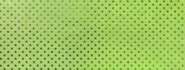 Fundo de natal verde claro de papel de folha de metal com um padrão de macro estrelas cintilantes Cenário verde-oliva