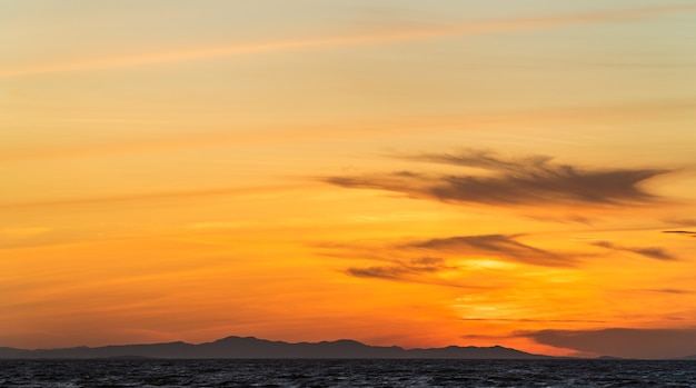 Fundo de nuvens do céu do sol com luz do sol laranja ao anoitecer sobre montanhas de silhueta