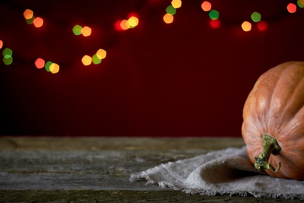 Fundo de outono em uma superfície de madeira escura, laranja abóbora em um fundo de luzes desfocadas