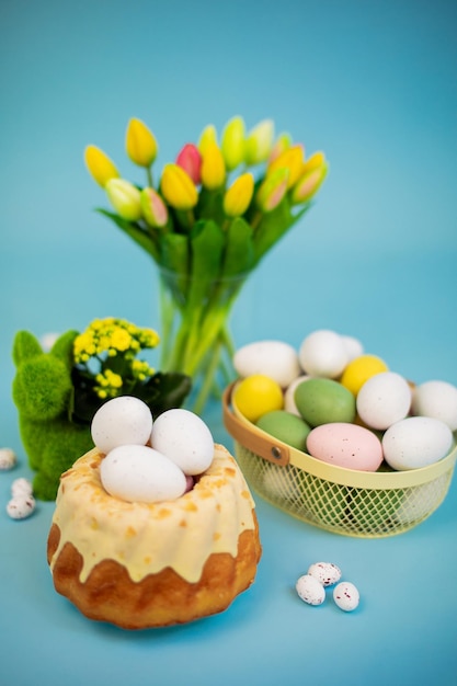 Fundo de páscoa com ovos coloridos bolo de páscoa flores de primavera em um fundo azul feliz páscoa