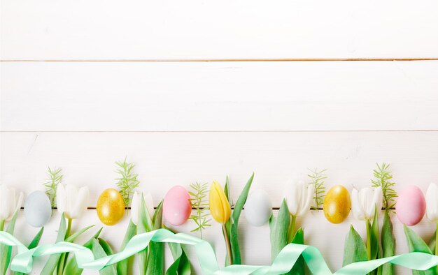 Fundo de páscoa com ovos de páscoa e vista superior de flores de primavera com espaço de cópia