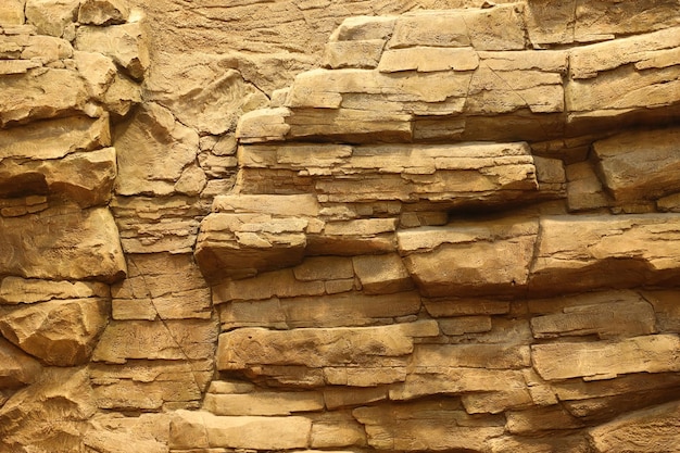 Fundo de pedra de rocha natural grosseira leve Superfície frontal áspera do penhasco de mineração Grande pano de fundo da pilha de calcário Grunge pesado danificado textura do bloco de granito