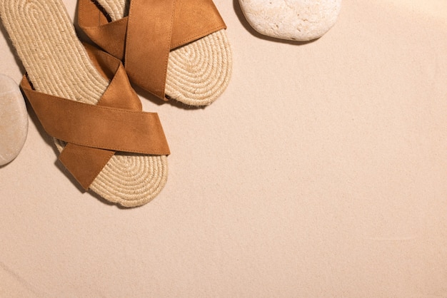 Fundo de praia com sandálias marrons e pedra em uma praia de areia nas férias de verão do conceito de sol em ...