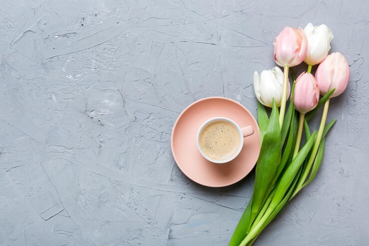 Foto fundo de primavera com flores uma xícara de café e um buquê de tulipas rosas e brancas em fundo de mesa colorida com lugar para texto copiar espaço vista superior