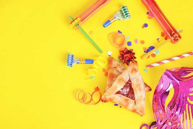 Fundo de Purim com máscara de carnaval, fantasia de festa e biscoitos hamantaschen.