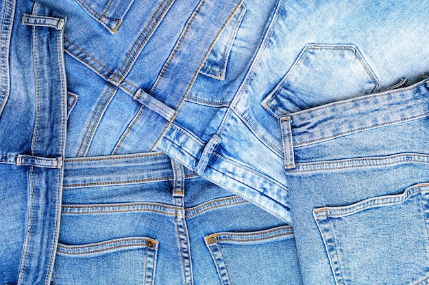 Fundo de textura de jeans, pilha de jeans, superfície de tecido de algodão azul claro com bolsos e costura com pontos de linha laranja