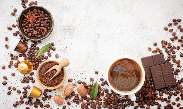 Fundo de vários grãos de café torrados escuros de café moídos e cápsulas com configuração de colheres em fundo de concreto branco com espaço de cópia