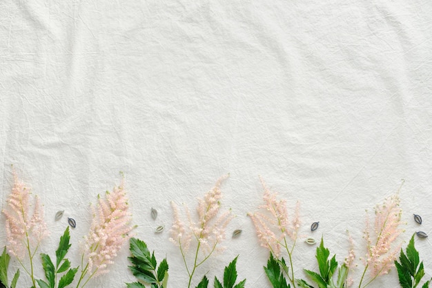 Fundo de verão natural com borda de flores silvestres copyspace lugar para texto flat lay off fundo de linho branco com flores prachtspiere selvagens rosa pálido