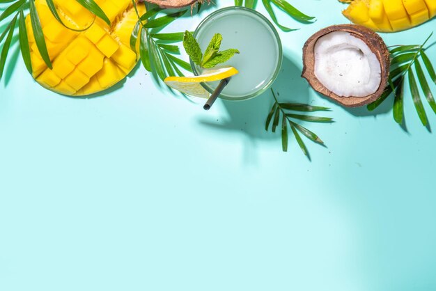 Fundo de verão tropical com chapéu manga coco frutas tropicais folhas de palmeira fones de ouvido férias de verão férias flatlay conceito de viagens de lazer vista superior espaço de cópia para texto