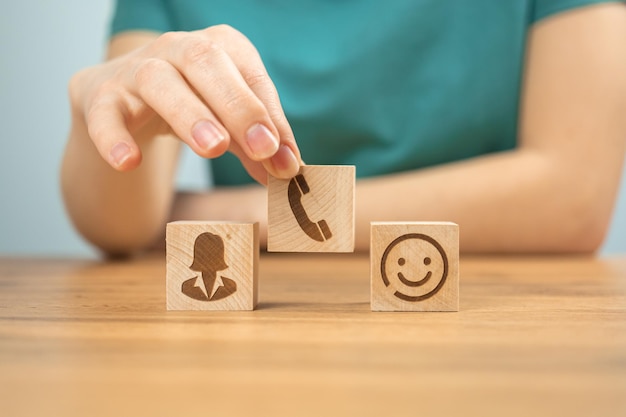 Fundo do conceito de serviço de call center Ajude o atendimento ao cliente e suporte Cubos de madeira com ícones e mão de jovem no escritório foto