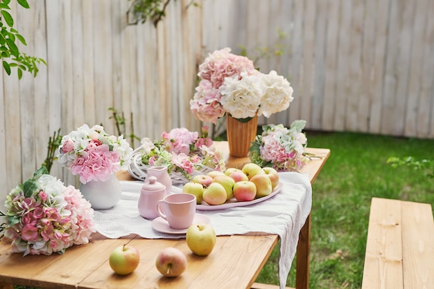 Fundo do jardim de verão. Buquê de flores de hortênsias e uma xícara de chá na mesa. Bom dia aconchegante. Piquenique na natureza. Cartão do dia das mães. Celebração