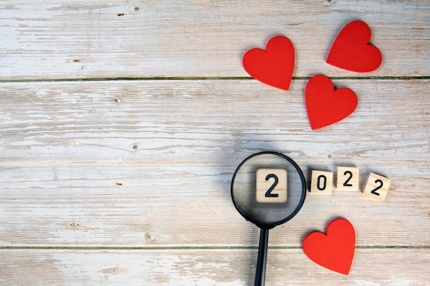 Fundo do símbolo do dia dos namorados 2022 ano e corações vermelhos no design romântico de fundo de madeira